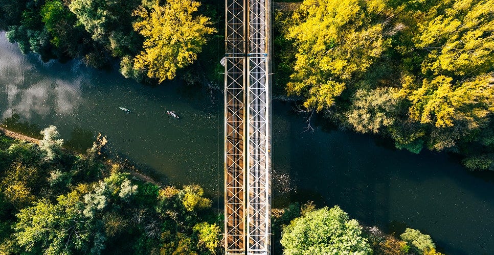 Aerial view of a bridge spanning over a river surrounded by dense trees