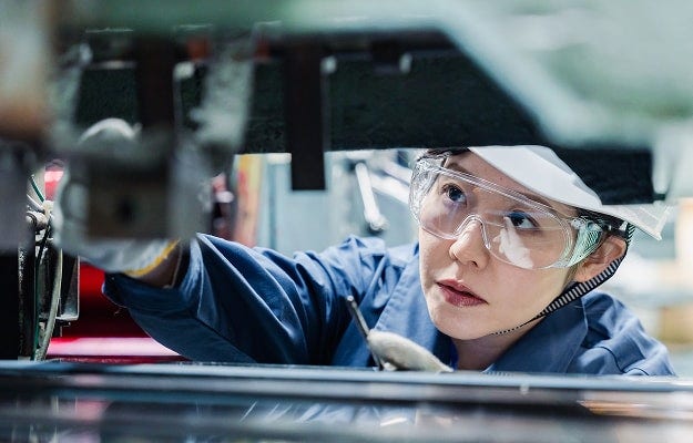 A person wearing a uniform and safety gear, engaging in a mechanical or technical task