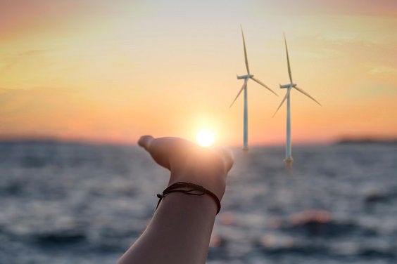Female hand reaches for the sun at sunset against the background of the sea.