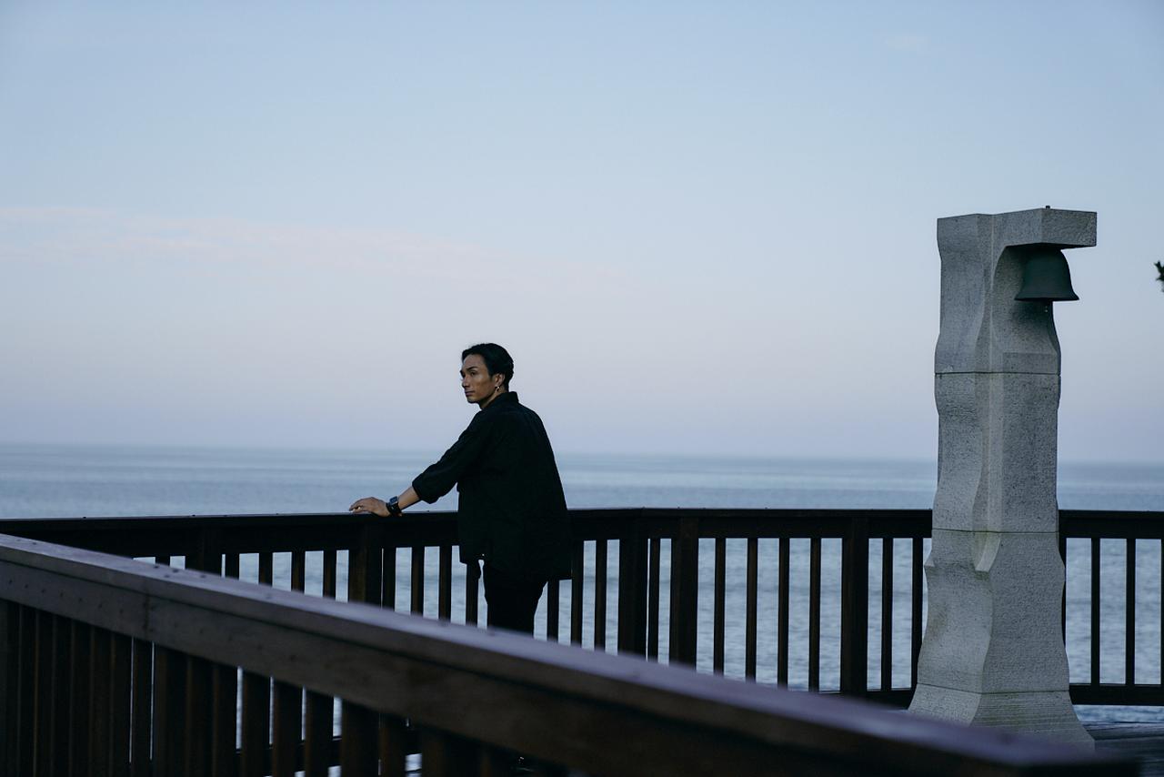 画像: 夕暮れの心地よい海風と眺望を楽しむ橘さん