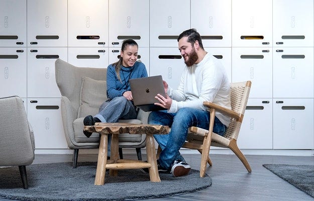 Two people sitting together engaged in conversation while looking at a laptop