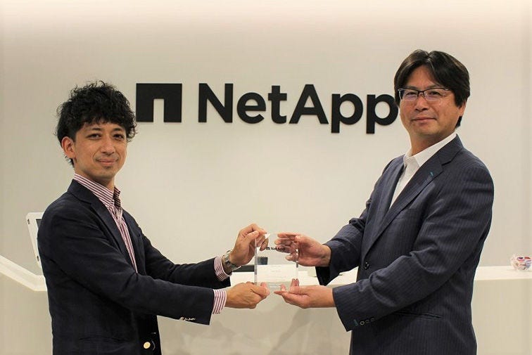 写真：ネットアップ合同会社 専務執行役員 ソリューション技術本部 本部長 平松 貢様、日立 金融第二システム事業部 金融システム第五本部 技師 星 宏慶