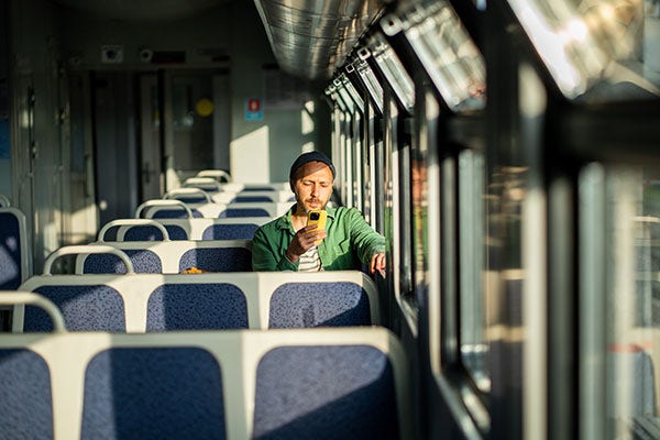 Focused man traveling to work on train with smartphone scrolling social media. Commuter routine. 