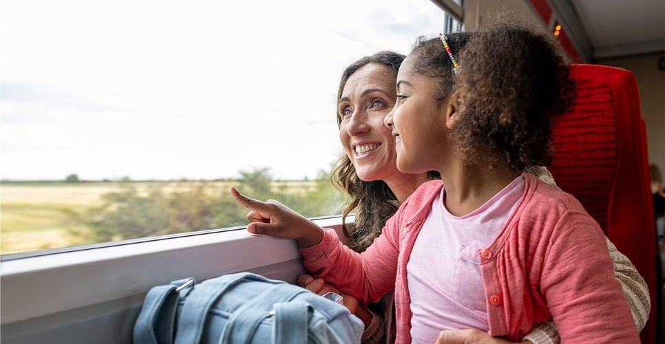 An adult and child sitting closely together looking out of a window