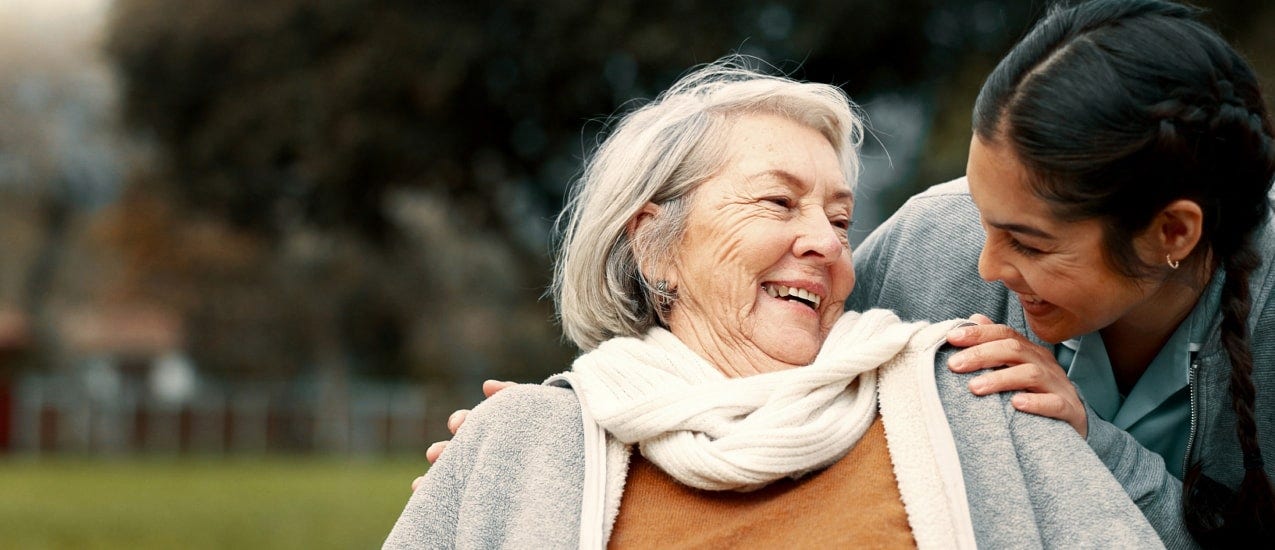 An older and a younger person smiling at each other