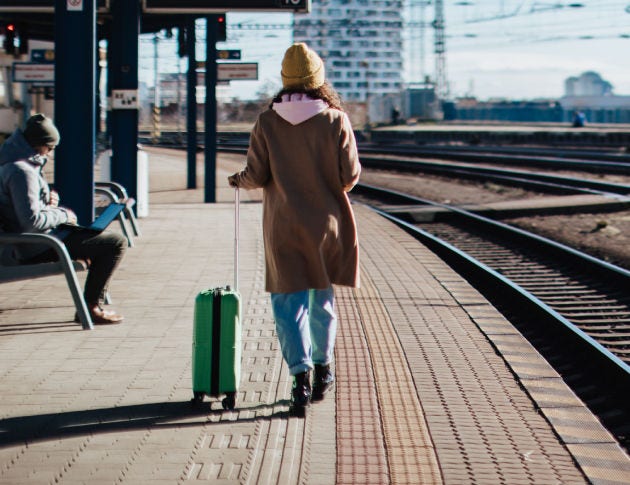 Traveler waiting at a railway platform, representing the everyday systems people depend on for mobility