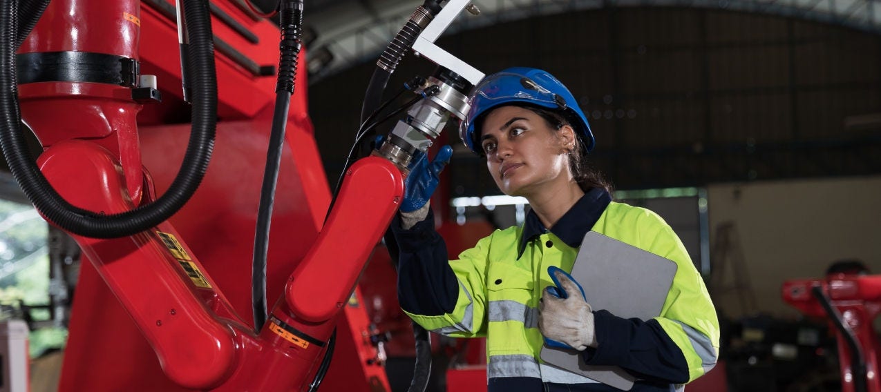 Worker interacting with robotic equipment in an industrial environment, illustrating the connection between people and automation