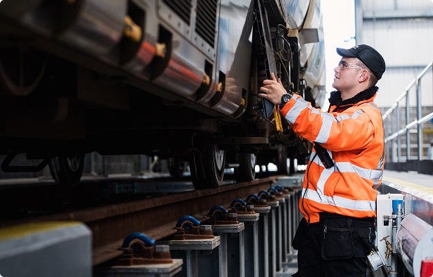A person wearing safety gear working on a train