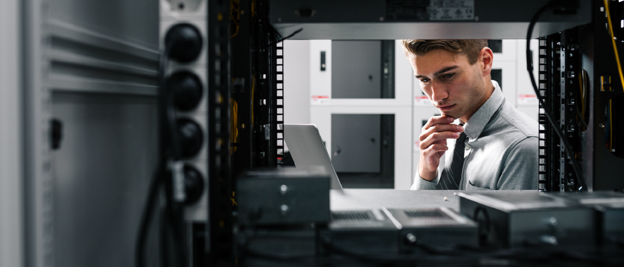 A guy looking holding a laptop looking inside a data system