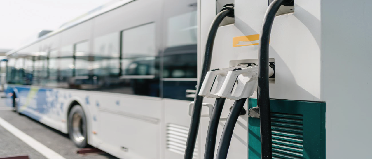 White electric bus at a charging station